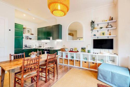 - une cuisine avec des placards verts et une table à manger en bois dans l'établissement Beautiful 1 bedroom apartment in Shepards Bush, à Londres