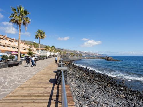 un paseo marítimo en una playa con palmeras y el océano en Live Candelaria Tres Carabelas, en Candelaria