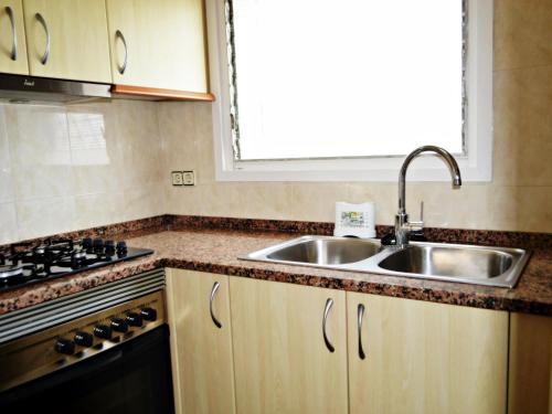 ピネダ・デ・マールにあるAFRODITA Casa con dos apartamentos independientesのキッチン(シンク、コンロ付)、窓が備わります。