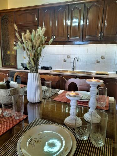 a kitchen table with a vase of flowers and candles at VILLA CHRYSANTHOS in Ágios Matthaíos