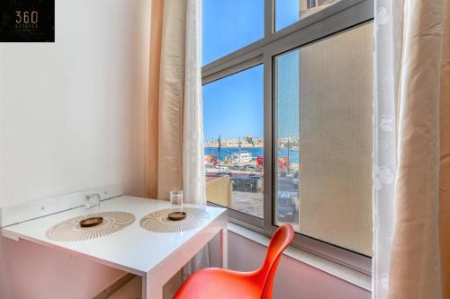 uma casa de banho com 2 lavatórios e uma cadeira vermelha em The Sliema Studio Stay by 360 Estates em Sliema