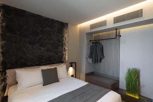 a bedroom with a bed with a black stone wall at Apikia Santorini in Pirgos