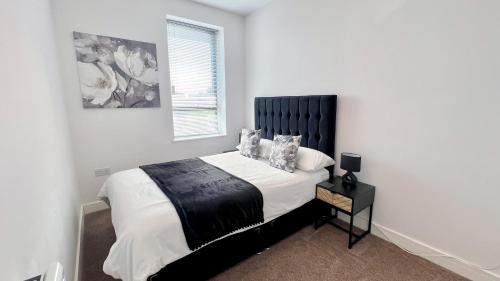 a bedroom with a bed with white walls and a window at Friars House, Stafford by BELL Apartments in Stafford