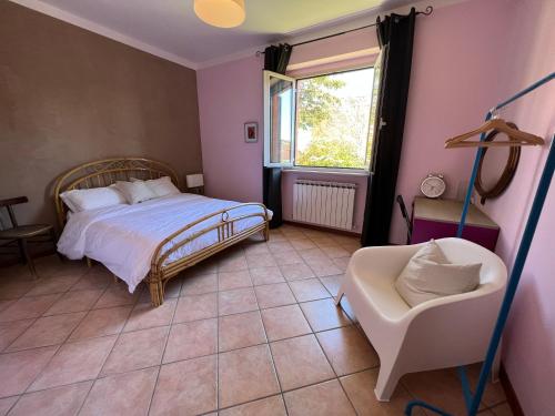 a bedroom with a bed and a chair and a window at casa mimose rosa II in SantʼAngelo in Pontano