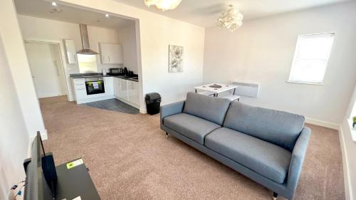 a living room with a blue couch and a kitchen at Friars House, Stafford by BELL Apartments in Stafford
