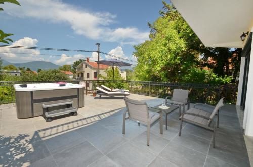 a patio with a hot tub and chairs and a table at Kjara Lux Apartment in Tivat
