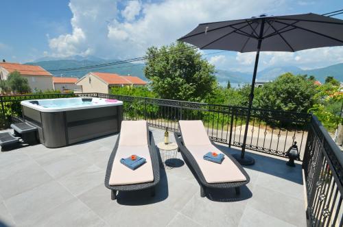 a patio with a hot tub and two chairs and an umbrella at Kjara Lux Apartment in Tivat