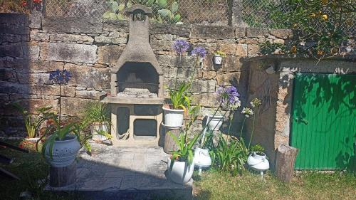 a garden with a stove and potted plants next to a stone wall at Chalet Lanzada in Sanxenxo