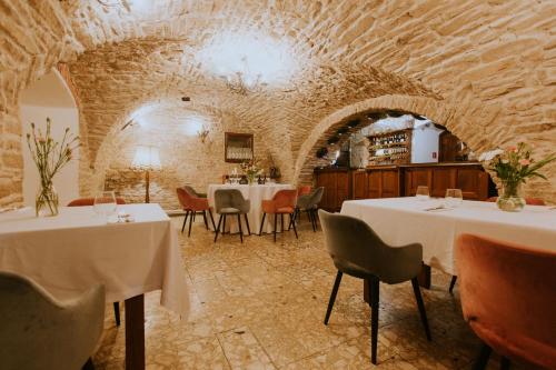 a restaurant with tables and chairs in a stone room at Dwór Zbożenna in Przysucha
