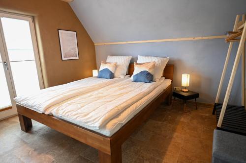 a bedroom with a large bed with two blue pillows at Ferienhaus PuddeWohl in Puddemin