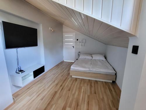 um pequeno quarto com uma cama e uma televisão em Apartament Świetlińska 17 em Ostróda