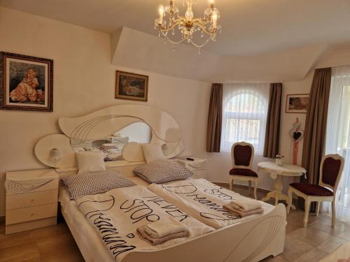 a bedroom with a large bed and a chandelier at Andrea Villa Keszthely in Keszthely