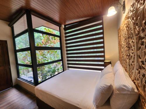 a bedroom with a bed and a large window at Wild Cassia in Haputale