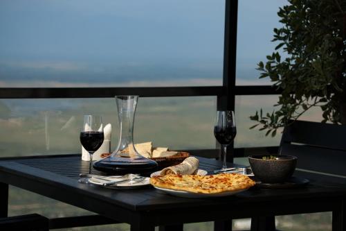 a table with two slices of pizza and two glasses of wine at Signagi Glamping in Sighnaghi