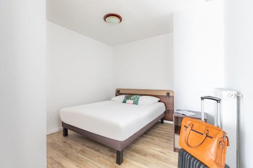 a bedroom with a bed and a suitcase at Appart'City Classic Chalon sur Saone in Chalon-sur-Saône