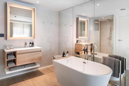 a white bathroom with a tub and a sink at INNSiDE by Meliá Zaragoza in Zaragoza