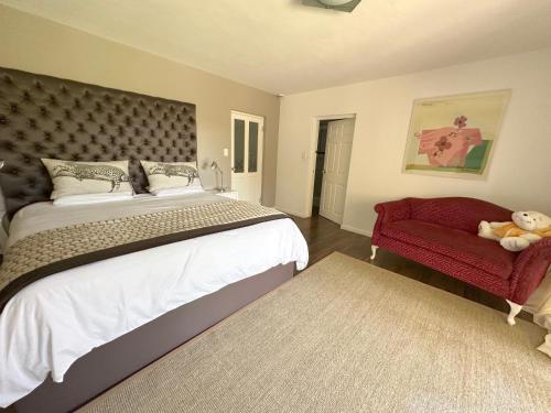 una camera con un grande letto e una sedia rossa di Monte Rosso Appartement a Somerset West