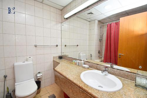 a bathroom with a toilet and a sink and a mirror at Luxury Escapes - Tranquil Studio Near Furjan Metro - Relaxing Holiday Retreat in Dubai