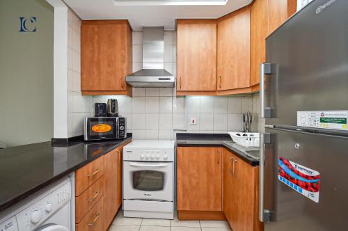 a kitchen with wooden cabinets and white appliances at Luxury Escapes - Tranquil Studio Near Furjan Metro - Relaxing Holiday Retreat in Dubai