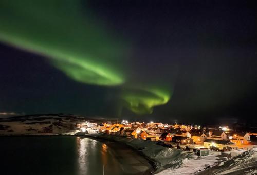 una imagen de la aurora sobre una ciudad en Bugøynes en Bugøynes