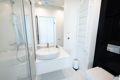 a white bathroom with a sink and a shower at WAVE private apartment - Fancy Sunset in Międzyzdroje