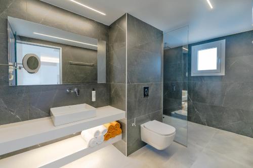 bagno con servizi igienici, lavandino e specchio di Thimios Suites Adults Only ad Acharavi