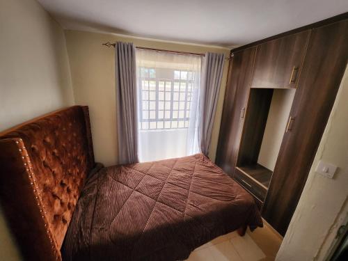 Habitación pequeña con cama y ventana en Zuri Homes 2 en Keruguya