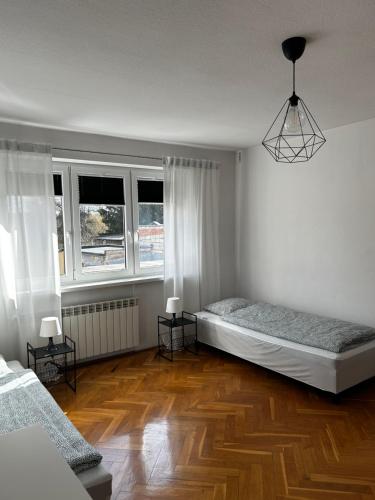 Cette chambre blanche comprend 2 lits et 2 fenêtres. dans l'établissement Hostel Centrum NT, à Nowy Tomyśl