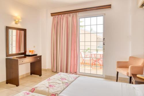 a room with a bed and a desk and a window at Oscar Hotel in Laganas