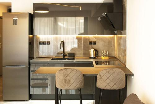 a kitchen with two bar stools and a refrigerator at P J Luxury Suites in Serres