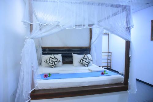 a bedroom with a canopy bed with white curtains at Enjoy River Cottage in Udawalawe