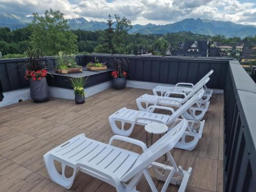 a row of white chairs and tables on a roof at Harenda in Zakopane