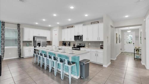 a kitchen with white cabinets and a large island with stools at 1840 Caribbean View in Kissimmee