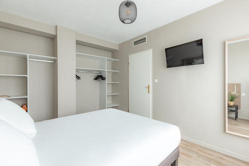 a bedroom with a white bed and a flat screen tv at Appart'City Classic Bordeaux Centre in Bordeaux