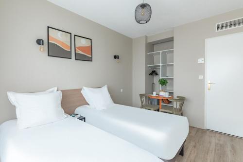 two white beds in a room with a table at Appart'City Classic Bordeaux Centre in Bordeaux