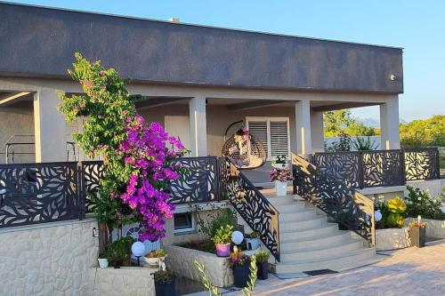 een vrouw op de veranda van een huis met bloemen bij Villa Dalmatia in Slivnica