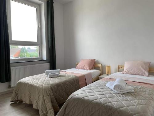 a room with two beds with towels and a window at Agréable duplex proche de toutes commodités in Ans