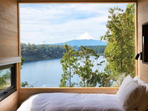 a bedroom with a large window with a view of a mountain at Exclusiva Cabin en tranquilo campo a orillas del lago con vista a volcanes - hot tub privado in Frutillar