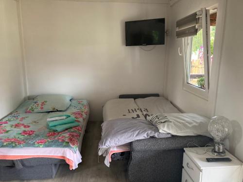 sypialnia z dwoma łóżkami i telewizorem na ścianie w obiekcie Domek u Franka w Smołdzinie
