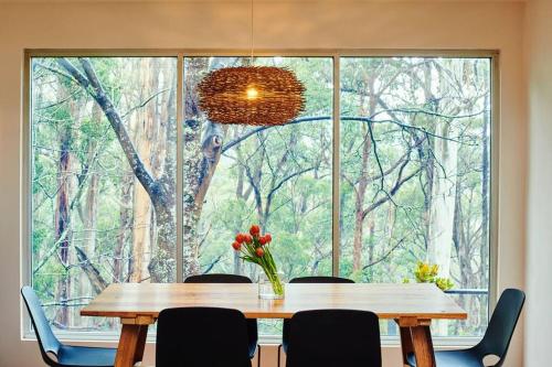 a dining room table with chairs and a large window at Mistwood - Cosy FirePlace in Mount Macedon