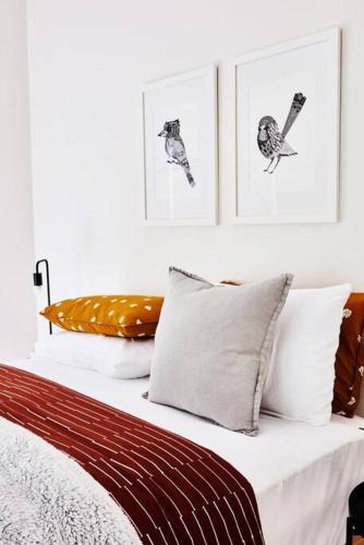 a bed with white pillows and pictures on the wall at Romantic Getaway - 2 luxe outdoor baths in Mount Macedon
