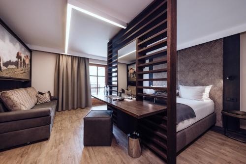 a bedroom with a bed and a desk and a couch at Familienresort Ellmauhof - das echte All Inclusive in Saalbach Hinterglemm