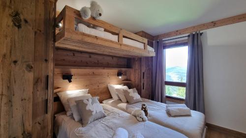 a bedroom with two beds with a stuffed dog sitting on them at Arcs 1950 Appartement Luxe type chalet 5 à 7 personnes Vue imprenable sur le Montblanc skis aux pieds in Arc 1950