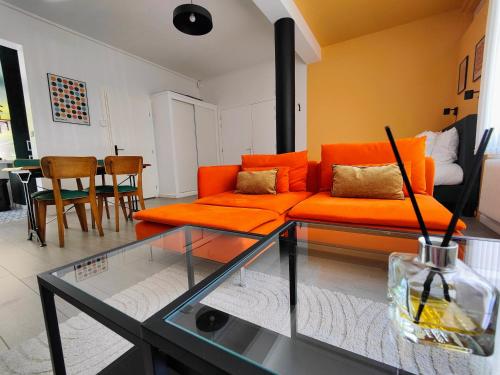 salon z pomarańczową kanapą i stołem w obiekcie Le Rainbow - Grand studio avec terrasse w mieście Dunkierka