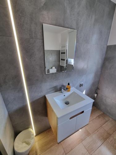La salle de bains est pourvue d'un lavabo blanc et d'un miroir. dans l'établissement Apartamenty Welskie, à Lidzbark