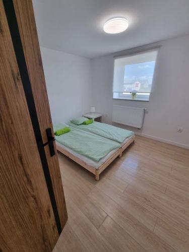 Schlafzimmer mit einem Bett, einem Fenster und einer Tür in der Unterkunft Apartamenty Welskie in Lidzbark