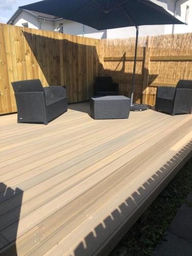 a wooden deck with two chairs and an umbrella at Millwood in Aviemore