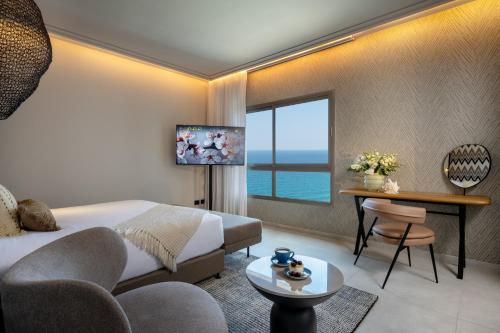 ein Hotelzimmer mit einem Bett, einem Tisch und einem Fenster in der Unterkunft Leonardo Plaza Haifa in Haifa