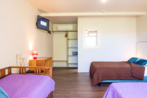 Zimmer mit 2 Betten und einem TV an der Wand in der Unterkunft Hotel ILOMA Corail Residence in Sainte-Luce