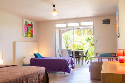 a bedroom with two beds and a table and a window at Hôtel Iloma in Sainte-Luce